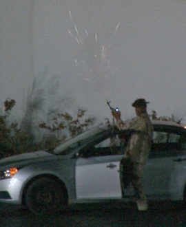 Qaddafi loyalist firing a gun in front of hotel.
