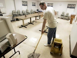 Homeless veteran mops the floor of the dining room at Scott Place shelter, Fairmont, West Virginia
