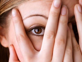 A young teen girl looking at the camera between her fingers