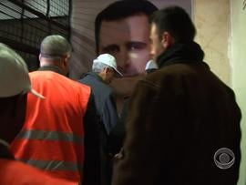 Observers from the Arab League arrive at the Damascus Criminal Justice Headquarters, where the image of Syrian president Bashar al-Assad is prominent on the walls.