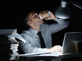 Manager working in office at night and drinking coffee at his workplace