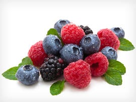 Mix of differrerent berries with mint leaves. Isolated on white.