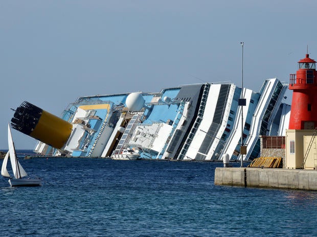A small dinghy sails past the stranded Costa Concordia cruise ship near the harbor of Giglio Porto June 25, 2012, in Italy.