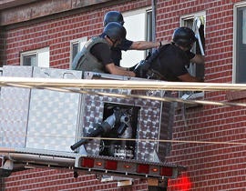 An Aurora Police officer talks on his radio outside of the Century 16 theater at Aurora Mall where as many as 14 people were killed and many injured at a shooting at the Century 16 movie theatre in Aurora, Colo., Friday, July 20, 2012.