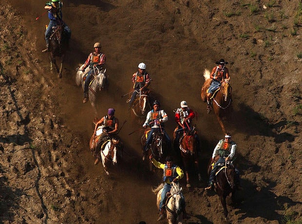 Participants in the Omak Suicide Race ride down a 62-degree slope to the Okanogan River August 15, 2004 in Omak, Washington.