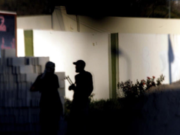 Members of Libya's Ansar al-Sharia Brigades stand in front of the gate of their compound