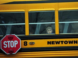 A child looks out of a bus window as it passes by St. Rose of Lima Catholic Church, where the funeral of James Mattioli, 6, was taking place Dec. 18, 2012, in Newtown, Conn.