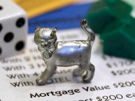 The newest Monopoly token, a cat, rests on a Boardwalk deed next to a die and houses at Hasbro Inc. headquarters, in Pawtucket, R.I., Tuesday, Feb. 5, 2013. Voting on Facebook determined that the cat would replace the iron token.