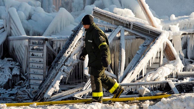 A police investigator looks over the frozen rubble after a fire destroyed a seniors residence in L'Isle-Verte, Quebec, Jan. 23, 2014.