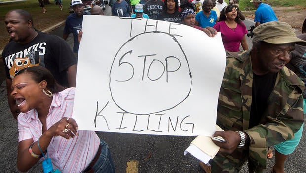 K.K. Davis, left, and Tommy Jones of Hearne, Texas, carry a sign with other protesters outside the Hearne Police Department May 8, 2014, following the shooting two days earlier of a 93-year-old woman.