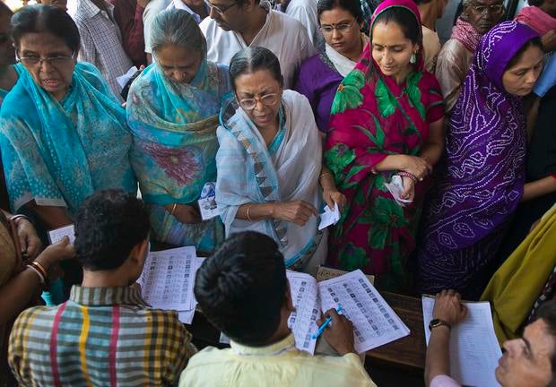 Voters get their names checked in a voter's lists at a polling station during the final phase of the general election in Varanasi
