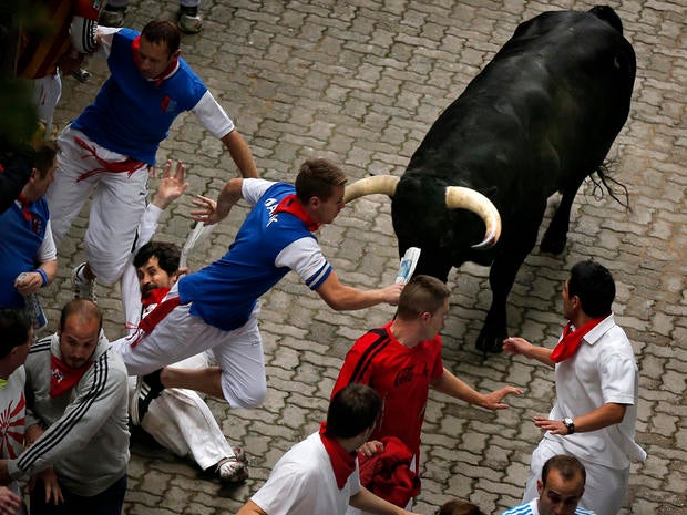 U.S. runner Bill Hillmann, 35, from Chicago, center left, falls seconds before a Victoriano del Rio ranch fighting bull gored him on his right leg during the running of the bulls at the San Fermin festival in Pamplona, Spain, July 9, 2014.