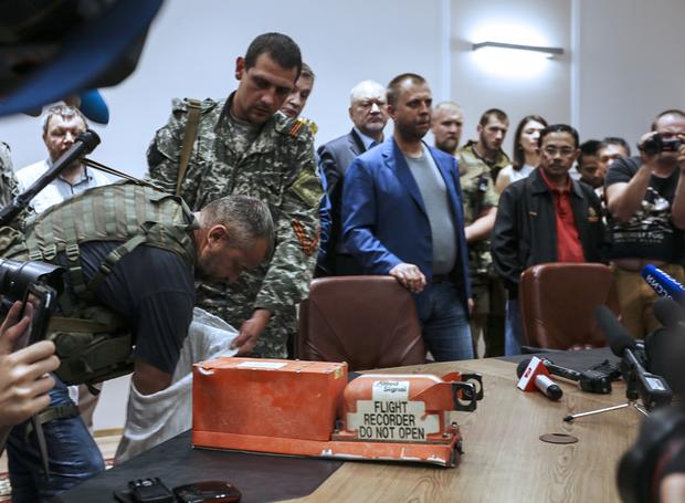 A pro-Russia separatist shows members of the media a "black box" from Malaysia Airlines flight 17, before handing it over to Malaysian representatives during a press conference in Donetsk