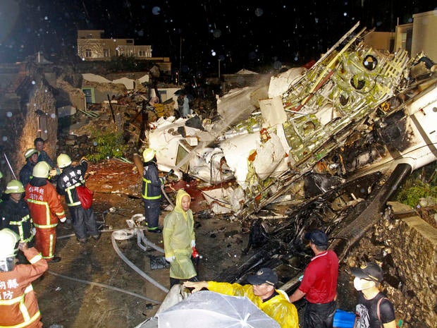 Rescue workers work next to the wreckage of TransAsia Airways Flight GE222, which crashed while attempting to land in stormy weather on the Taiwanese island of Penghu July 23, 2014.