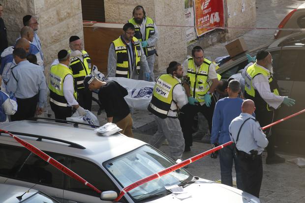 Israeli emergency service volunteers carry the body of a Palestinian assailant who was shot dead while attacking a synagogue in the ultra-Orthodox Har Nof neighborhood in Jerusalem