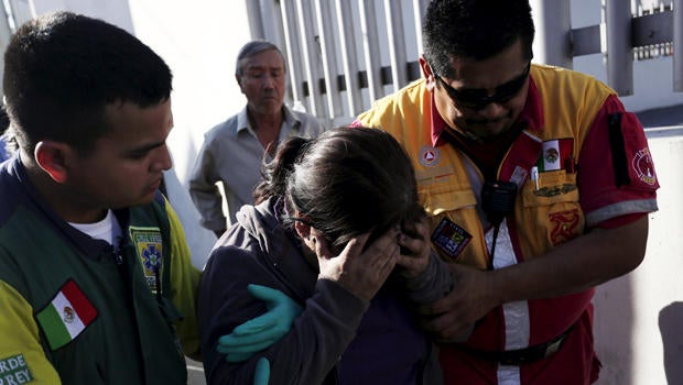 An inmate's family member is helped by a Green Cross worker and a Civil Protection worker outside the Topo Chico prison in Monterrey, Mexico, Feb. 11, 2016.