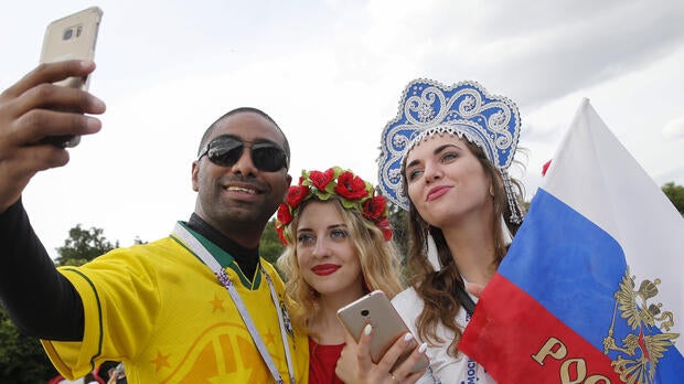 A Brazil fan takes a selfie with Russian supporters in a fan zone near the main building of the Moscow State University in Moscow on June 14, 2018.