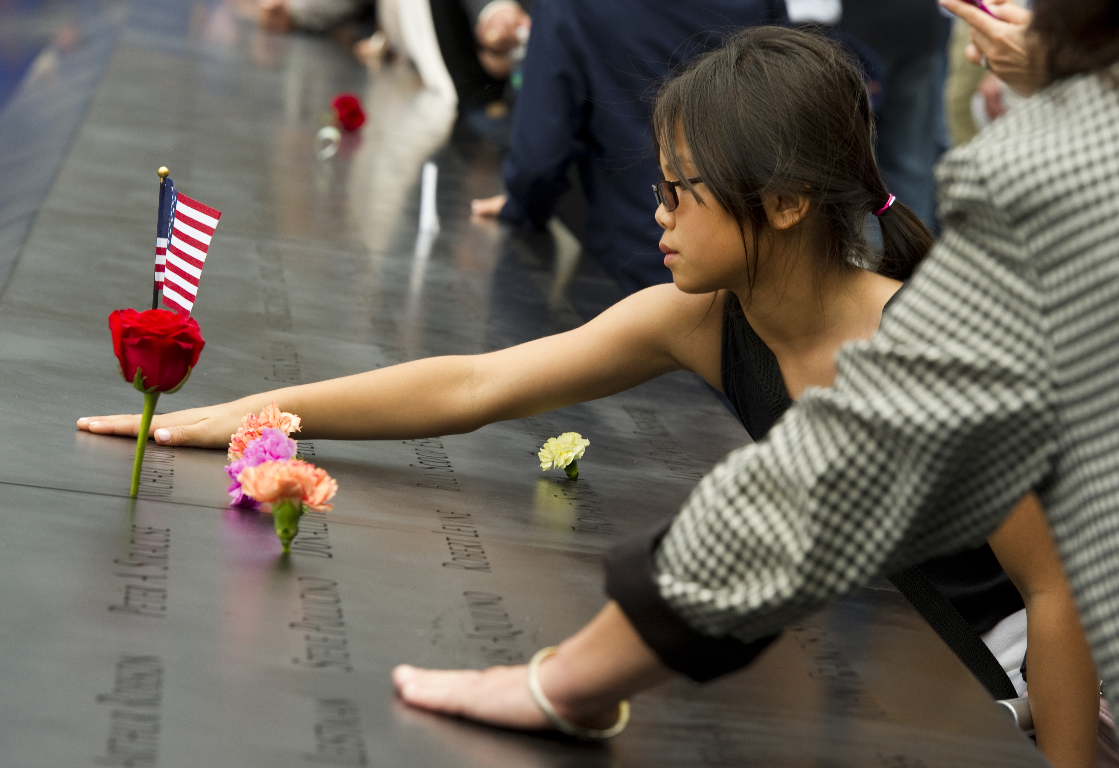 A young girl touches a name on the 9/11 Memorial  