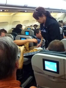 A Frontier Airlines flight attendant passes out pizza to passengers aboard a Denver-bound flight diverted to Cheyenne, Wyo., July 7, 2014. The airplane pilot treated his passengers to the pizza after they were diverted.