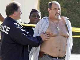 Police officers stand with who was being held in a patrol car at the scene of the arrest of a suspect near the Salon Meritage in Seal Beach, Calif., where a shooting left eight people dead and one critically injured Wednesday, Oct. 12, 2011. Seal Beach police have identified the suspect in the salon massacre as Scott Evans Dekraai.