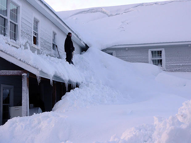 In this Saturday, Jan. 7, 2012 photo provided by the Alaska Division of Homeland Security and Emergency Management, a man stands on a house buried in snow in the fishing town of Cordova, Alaska.