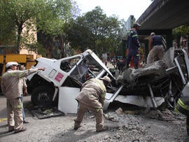 Firefighters work to remove a cement beam that fell from a bridge onto a public bus after an earthquake was felt in Mexico City Tuesday March 20, 2012. A strong 7.4-magnitude earthquake hit central and southern Mexico on Tuesday, collapsing at least 60 homes near the epicenter and a pedestrian bridge in the capital where people fled shaking office buildings in fear. There were no passengers in the mini-bus and the driver suffered minor injuries, according to firefighters.