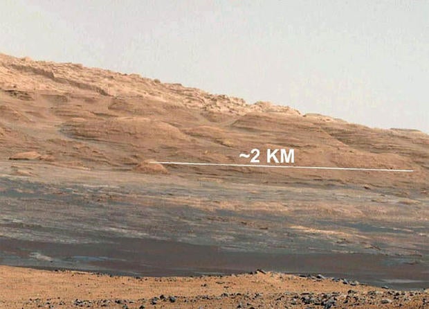 This image (cut out from a mosaic) shows the view from the landing site of NASA's Curiosity rover toward the lower reaches of Mount Sharp, where Curiosity is likely to begin its ascent through hundreds of feet (meters) of layered deposits. The lower several hundred feet (meters) show evidence of bearing hydrated minerals, based on orbiter observations. The terrain Curiosity will explore is marked by hills, buttes, mesas and canyons on the scale of one-to-three story buildings, very much like the Four Corners region of the western United States. A scale bar indicates a distance of 1.2 miles (2 kilometers). Curiosity's 34-millimeter Mast Camera acquired this high-resolution image on Aug. 8, 2012 PDT (Aug. 9 EDT). This image shows the colors modified as if the scene were transported to Earth and illuminated by terrestrial sunlight. This processing, called "white balancing," is useful to scientists for recognizing and distinguishing rocks by color in more familiar lighting. Image credit: NASA/JPL-Caltech/MSSS