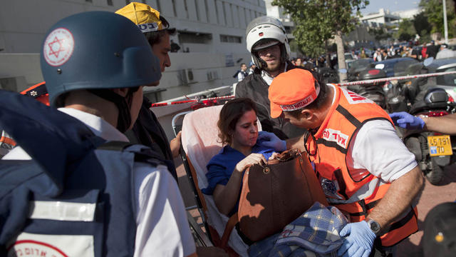 Israeli rescue workers and paramedics carry an injured woman from the site of a bombing in Tel Aviv, Israel, Wednesday, Nov. 21, 2012. A bomb ripped through an Israeli bus near the nation's military headquarters in Tel Aviv on Wednesday, wounding several  