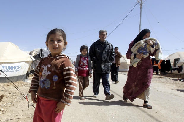 A Syrian family walks amid tents at the Zaatari refugee camp