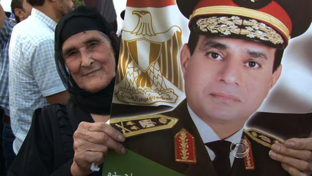 A woman holds a sign of Gen. Abdel Fattah al-Sisi's face.