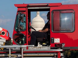 A firefighter sits in a firetruck near the scene on the National Mall in Washington where a man set himself on fire Oct. 4, 2013.