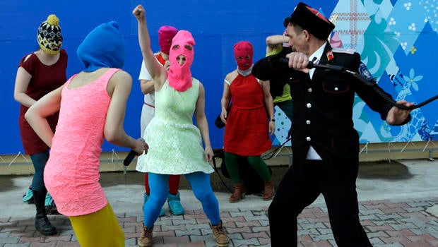 Members of the punk group Pussy Riot, including Nadezhda Tolokonnikova in the blue balaclava and Maria Alekhina in the pink balaclava, are attacked by Cossack militia in Sochi, Russia, Feb. 19, 2014.