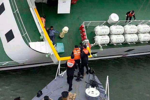 A passenger is rescued by South Korean maritime policemen from the sinking ship Sewol in the sea off Jindo April 16, 2014, in this picture provided by the Korean coast guard and released by Yonhap.