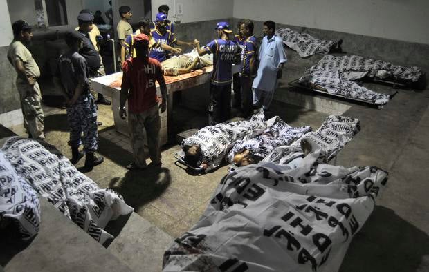 Rescue workers and paramilitary soldiers gather next to bodies after an attack on Jinnah International Airport, at a hospital morgue in Karachi