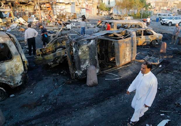 Man walks past the site of a car bomb attack in Baghdad's Sadr City