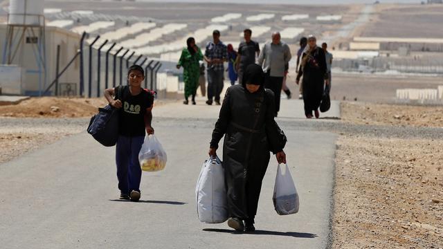 Newly-arrived Syrian refugees carry their belongings as they walk at Azraq refugee camp near Al Azraq area, east of Amman, Jordan, on August 19, 2014 