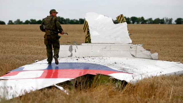 An armed pro-Russian separatist stands on part of the wreckage of the Malaysia Airlines Boeing 777 plane July 17, 2014, after it crashed near the settlement of Grabovo in the Donetsk region.