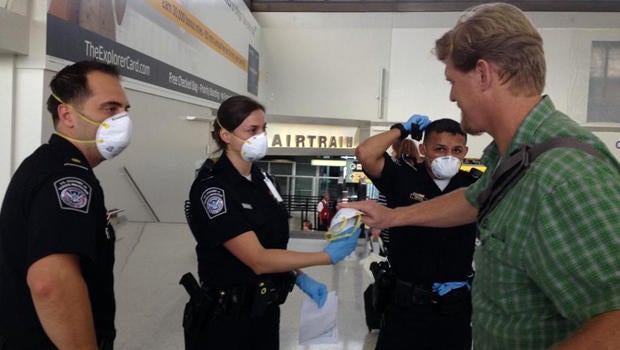 U.S. customs agents hand out surgical masks at Newark Liberty International Airport Oct. 4, 2014, after the Centers for Disease Control and Prevention removed a passenger from an international flight in Newark, N.J.