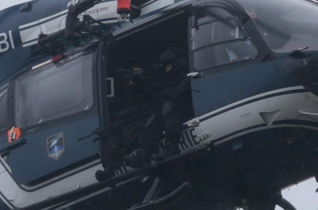 Members of the GIGN (National Gendarmerie Intervention Group) sit in a helicopter flying over Dammartin-en-Goele