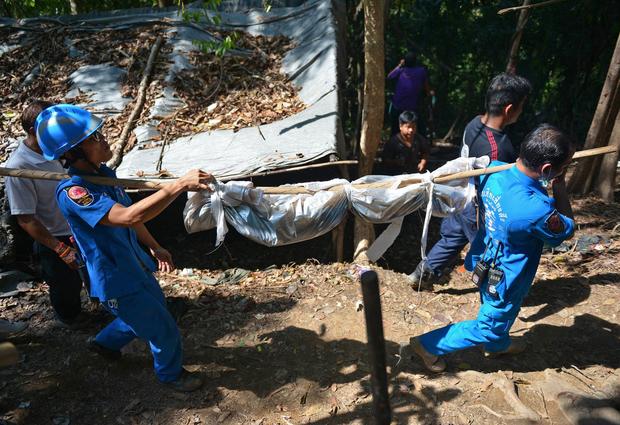 Rescue workers carry a body uncovered at the site of a mass grave at an abandoned jungle camp used to smuggle Rohingya Muslim migrants in the Sadao district of Thailand's southern Songkhla province bordering Malaysia