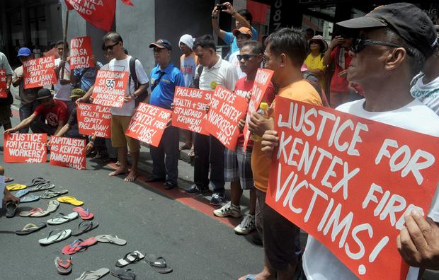 Protesters hold placards during a rally to call for justice for the victims of a fire that gutted a footwear factory the day before, in Manila