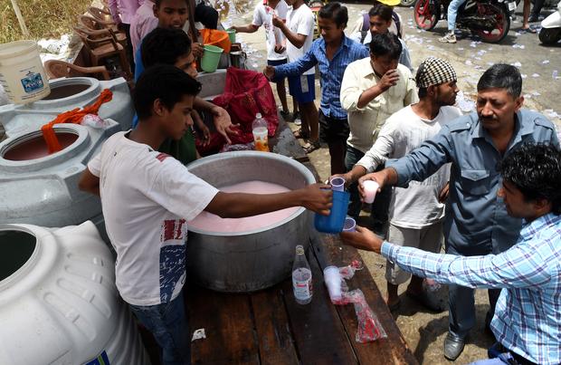 Indian volunteers distribute free cold sweet water on a street in New Delhi