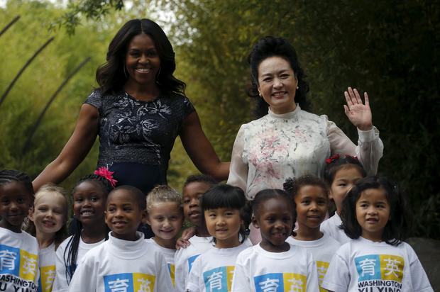 China's first lady Peng Liyuan, left, and U.S. first lady Michelle Obama pose for a picture with kids from Yu Ying Public Charter School during a visit to the Smithsonian Zoo in Washington Sept. 25, 2015.