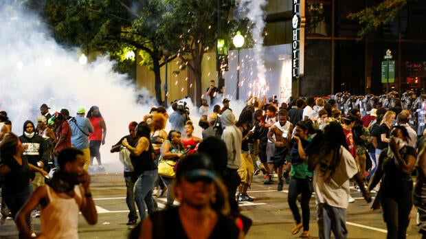 People run from flash-bang grenades in uptown Charlotte, North Carolina, during a protest of the police shooting of Keith Scott in Charlotte Sept. 21, 2016.