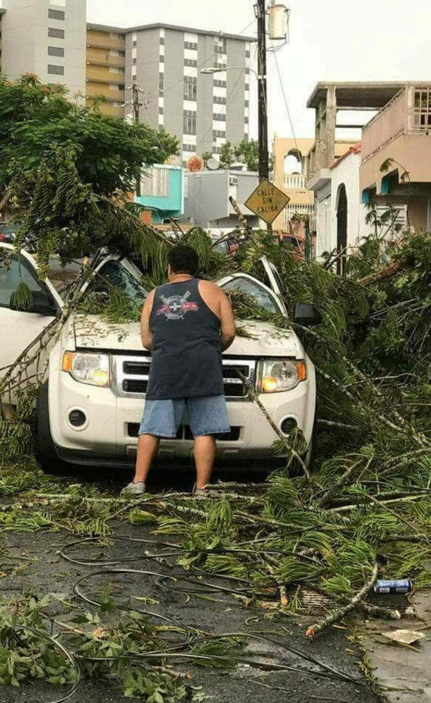 A man removes debris from a car following high winds as Hurricane Irma nears San Juan 