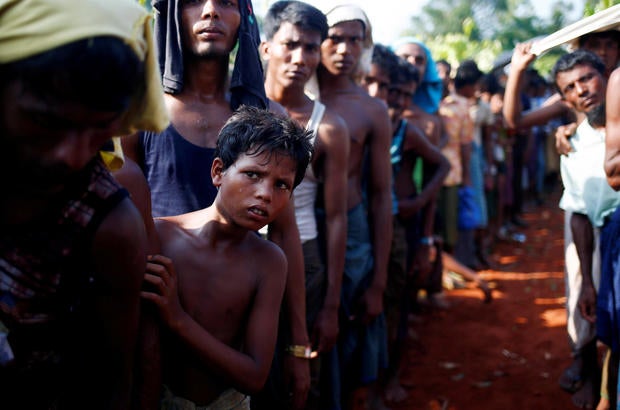 A Rohingya refugee boy looks on as he stands in a queue to receive relief supplies given by local people in Coxís Bazar