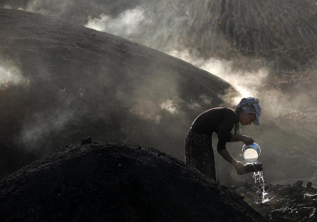 A woman sprays water on burning woods during a charcoal making process near Kizilcahamam 