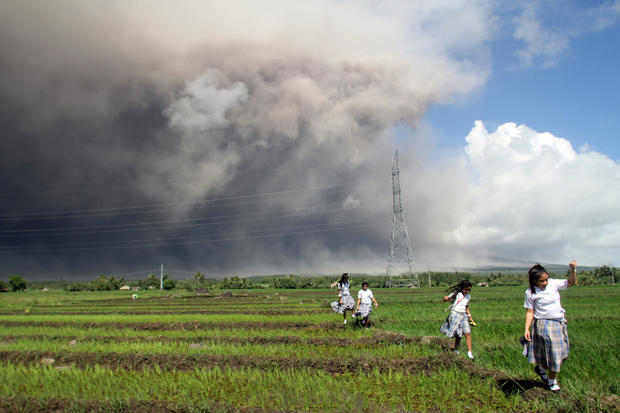 Students passes through the rice paddy as they run away from cascading volcanic materials from the slopes of Mayon Volcano in Guinobatan, Albay province, south of Metro Manila 