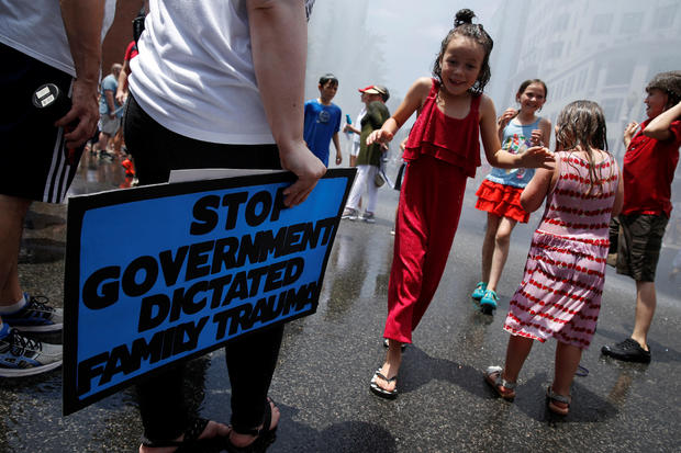 Children run through a spray of water during a rally by immigration activists to protest against the Trump Administration's immigration policy outside the White House in Washington 