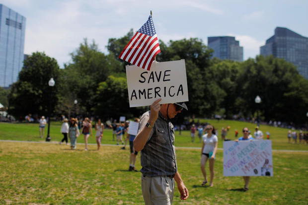 A demonstrator carries a sign reading "Save America" during the "Families Belong Together" rally in Boston 